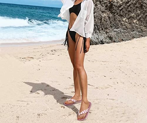 Woman in bikini and shirt standing on a sandy beach