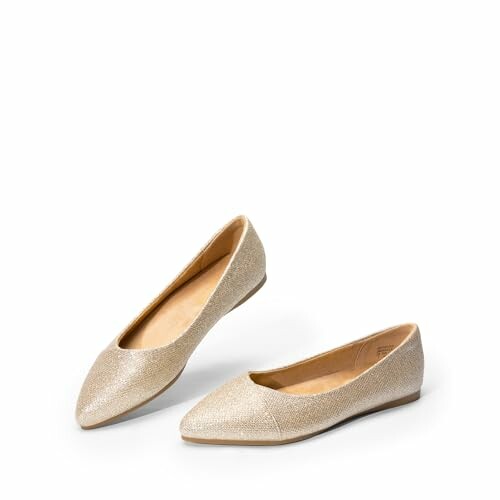 Pair of golden ballet flats on white background