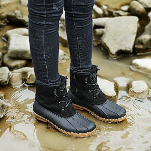 Person wearing waterproof boots standing on wet stones.